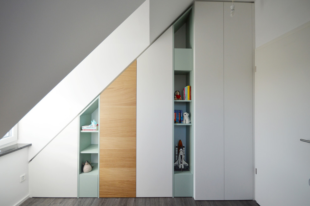 This is an example of a small contemporary gender-neutral built-in wardrobe in Munich with dark hardwood floors, grey floor, flat-panel cabinets and white cabinets.