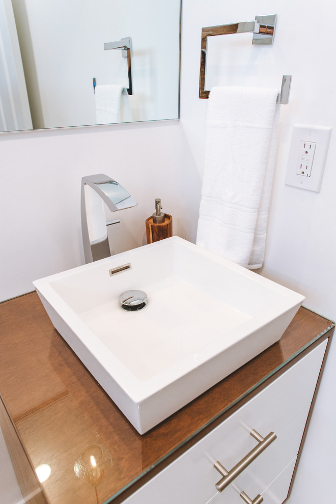 Design ideas for a small contemporary 3/4 bathroom in Orange County with furniture-like cabinets, medium wood cabinets, an alcove tub, a shower/bathtub combo, a one-piece toilet, white walls, ceramic floors, a vessel sink, glass benchtops, white floor and a sliding shower screen.