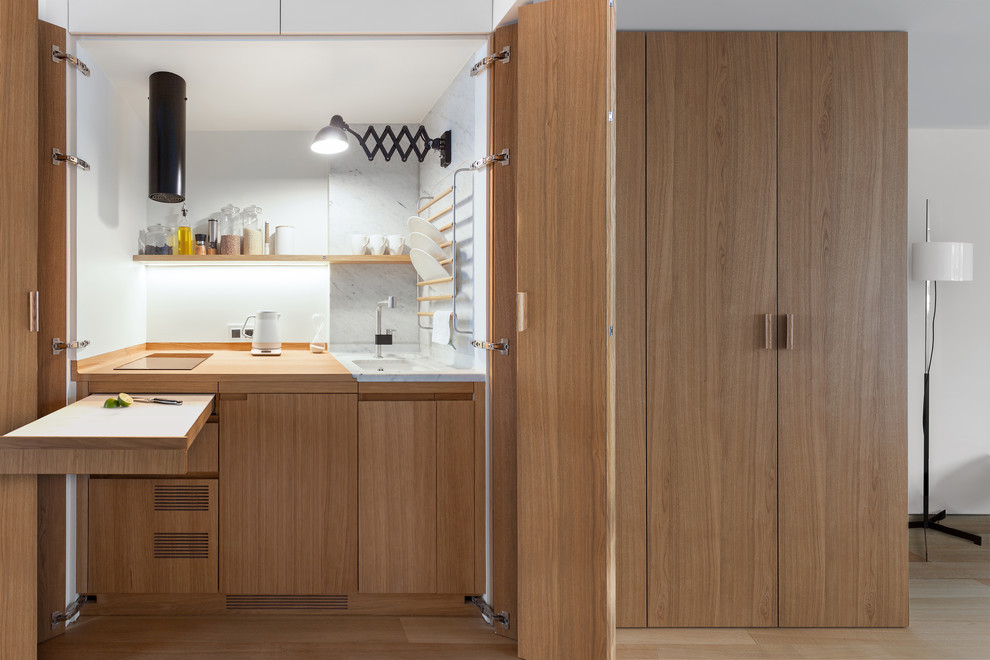 Photo of a small contemporary separate kitchen in Moscow with an undermount sink, medium wood cabinets, wood benchtops, white splashback, panelled appliances and medium hardwood floors.