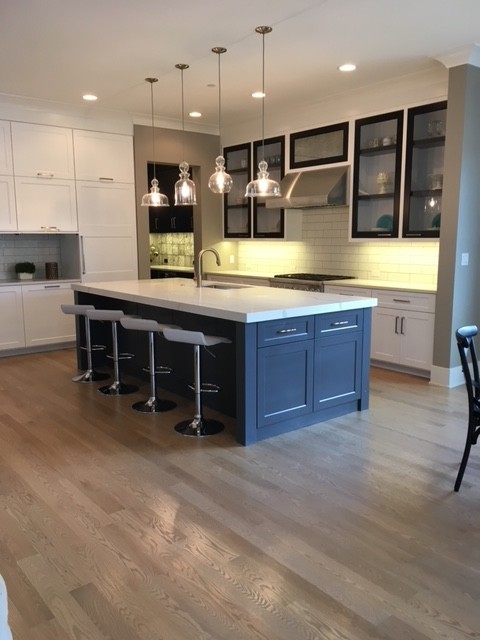 Example of a huge transitional l-shaped light wood floor and beige floor home design design in Chicago with an undermount sink, glass-front cabinets, white cabinets, quartz countertops, white backsplash, ceramic backsplash, paneled appliances, an island and white countertops