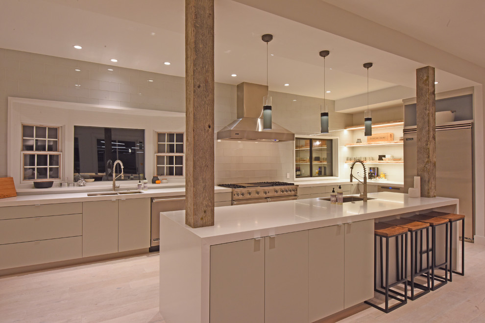 Inspiration for a rustic light wood floor eat-in kitchen remodel with an undermount sink, flat-panel cabinets, gray cabinets, white backsplash, stainless steel appliances, an island and white countertops