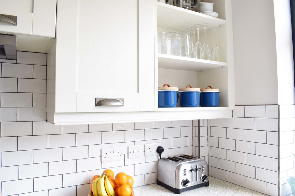 Photo of a medium sized contemporary u-shaped kitchen/diner with a belfast sink, shaker cabinets, blue cabinets, recycled glass countertops, white splashback, ceramic splashback, lino flooring, a breakfast bar and grey floors.