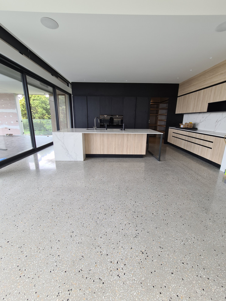 Inspiration for a medium sized contemporary l-shaped open plan kitchen in Melbourne with a submerged sink, flat-panel cabinets, light wood cabinets, marble worktops, white splashback, marble splashback, black appliances, concrete flooring, an island, grey floors and white worktops.