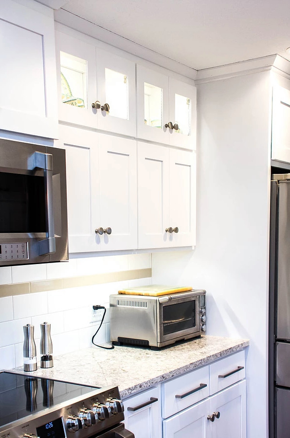 Enclosed kitchen - large transitional galley medium tone wood floor and brown floor enclosed kitchen idea with an undermount sink, white cabinets, quartzite countertops, white backsplash, stainless steel appliances, shaker cabinets, ceramic backsplash, a peninsula and multicolored countertops