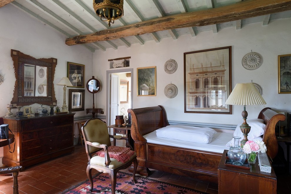 Country bedroom in Florence with white walls and terra-cotta floors.