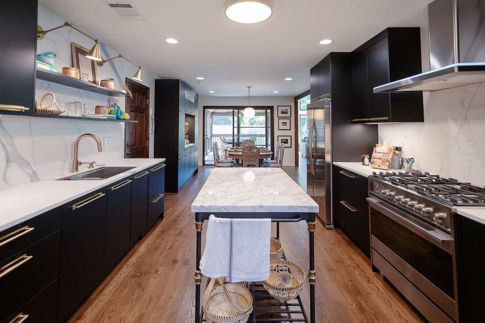 Contemporary galley kitchen in Atlanta with an undermount sink, flat-panel cabinets, black cabinets, white splashback, stainless steel appliances, medium hardwood floors, with island, brown floor and white benchtop.