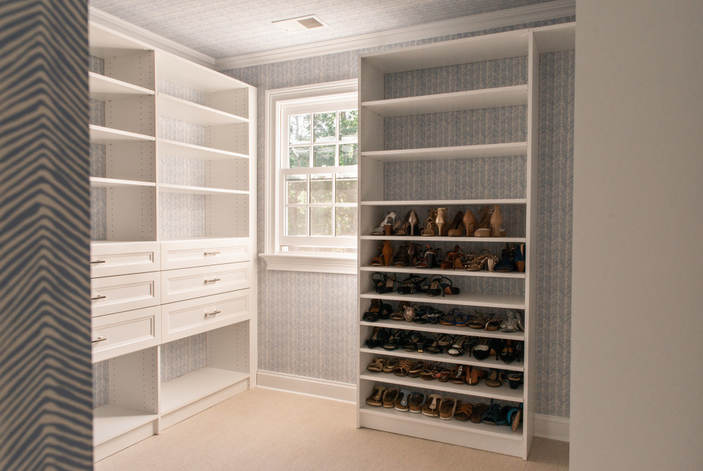 Mid-sized traditional gender-neutral walk-in wardrobe in New York with white cabinets and wallpaper.