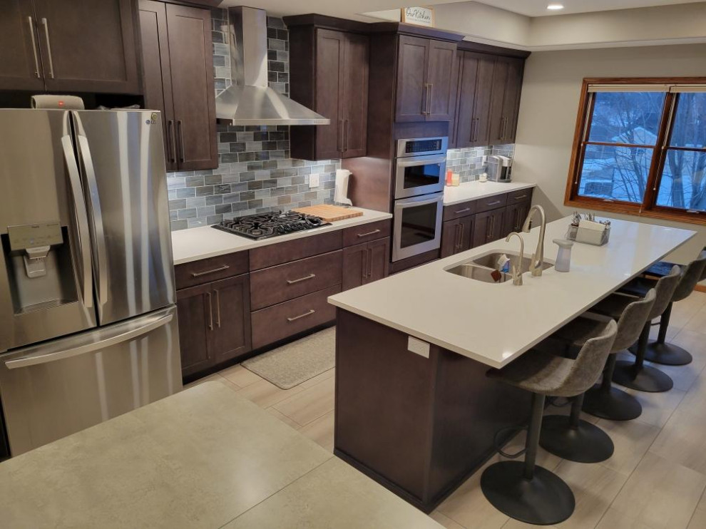 Large contemporary single-wall kitchen/diner in Nashville with a submerged sink, flat-panel cabinets, brown cabinets, engineered stone countertops, metro tiled splashback, stainless steel appliances, vinyl flooring, an island, beige worktops and a drop ceiling.
