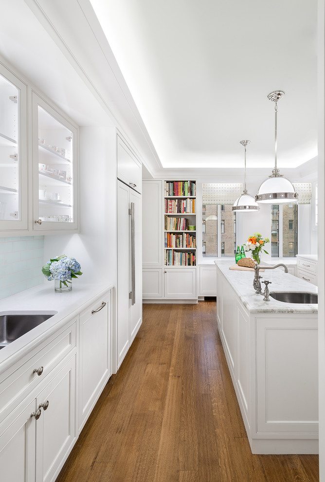 Design ideas for a traditional kitchen in New York with an undermount sink, recessed-panel cabinets, white cabinets, blue splashback, subway tile splashback, medium hardwood floors and with island.