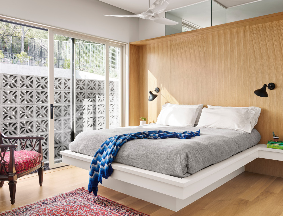 Foto di una camera da letto minimalista con pareti bianche, parquet chiaro e pareti in legno