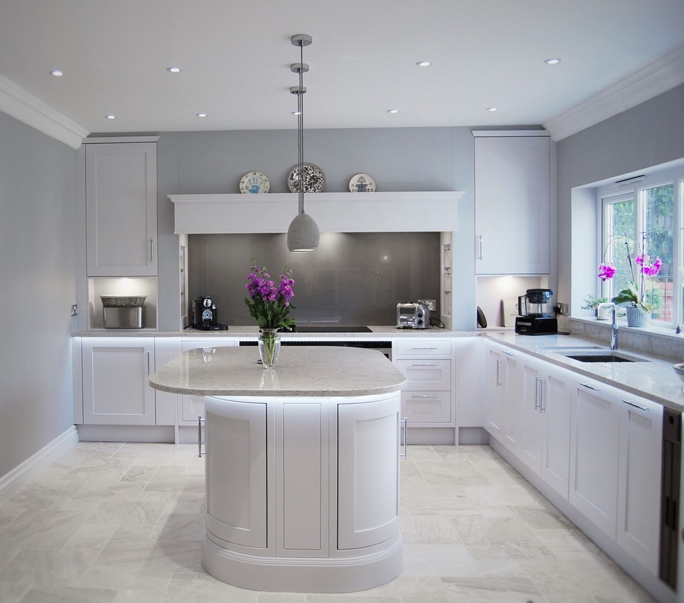 Inspiration for a transitional l-shaped kitchen in Surrey with an undermount sink, shaker cabinets, white cabinets, grey splashback, glass sheet splashback and with island.