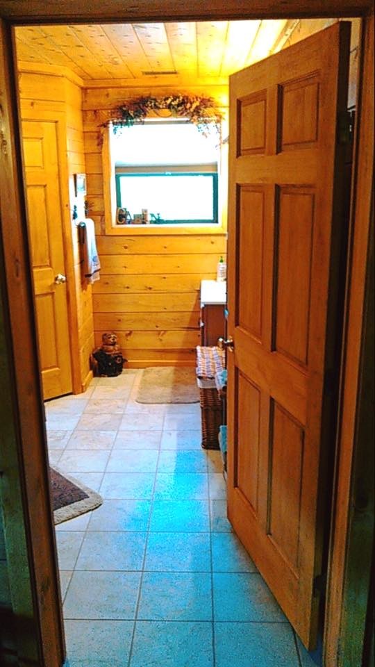 Photo of a mid-sized bathroom in Albuquerque with medium wood cabinets, a shower/bathtub combo, a one-piece toilet, beige tile, stone tile, brown walls, ceramic floors and concrete benchtops.