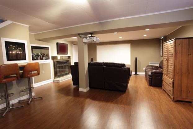 Example of a transitional medium tone wood floor basement design in Calgary with beige walls and a standard fireplace