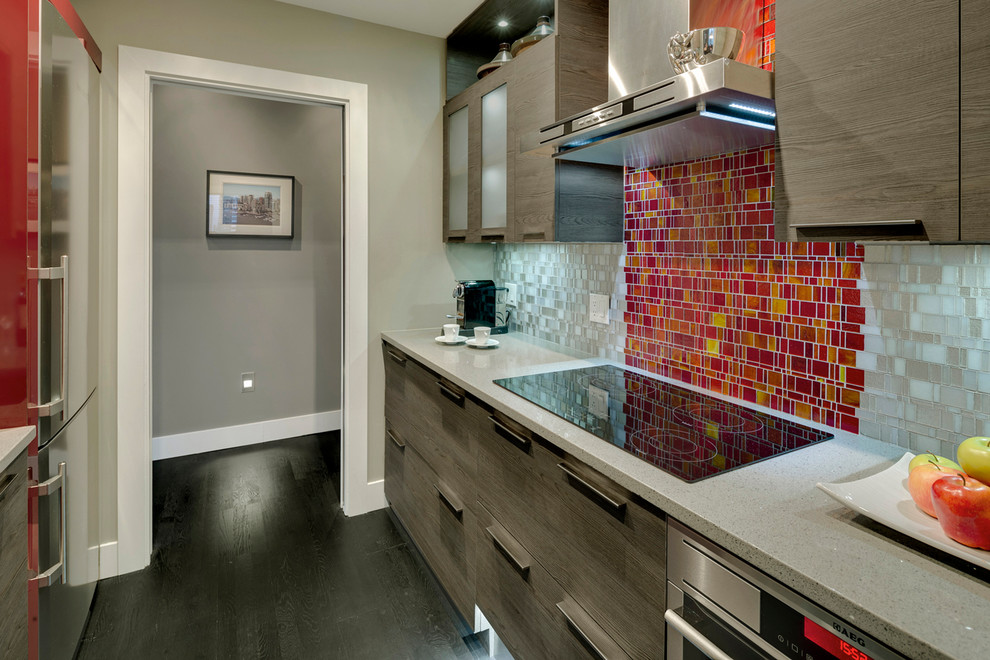 This is an example of a mid-sized eclectic galley kitchen in Vancouver with an undermount sink, flat-panel cabinets, dark wood cabinets, terrazzo benchtops, metallic splashback, glass tile splashback, stainless steel appliances, dark hardwood floors, no island and black floor.