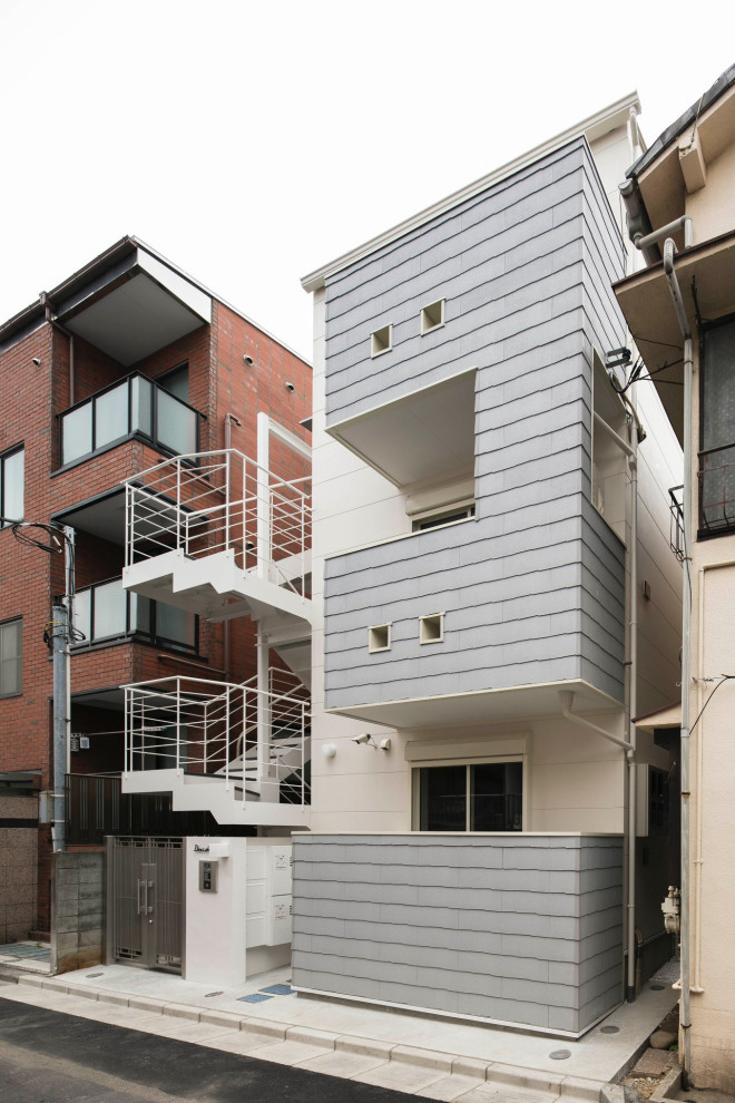 This is an example of a small scandinavian three-storey white house exterior in Tokyo with concrete fiberboard siding, a gable roof and a metal roof.