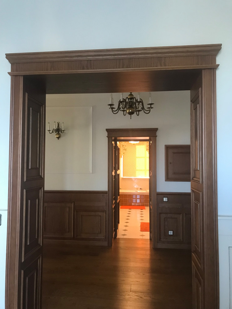 На фото: большой коридор: освещение в классическом стиле с коричневыми стенами, паркетным полом среднего тона, коричневым полом и панелями на части стены с
