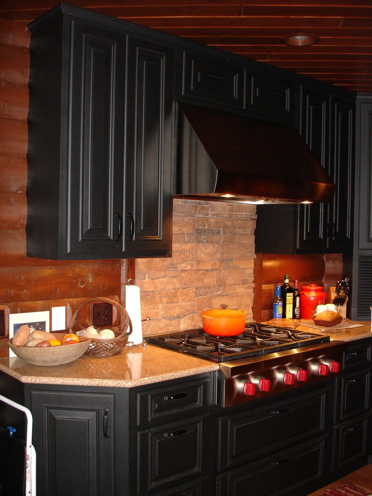 Example of a mid-sized mountain style single-wall medium tone wood floor and beige floor enclosed kitchen design with raised-panel cabinets, black cabinets, granite countertops, beige backsplash, wood backsplash, stainless steel appliances and no island
