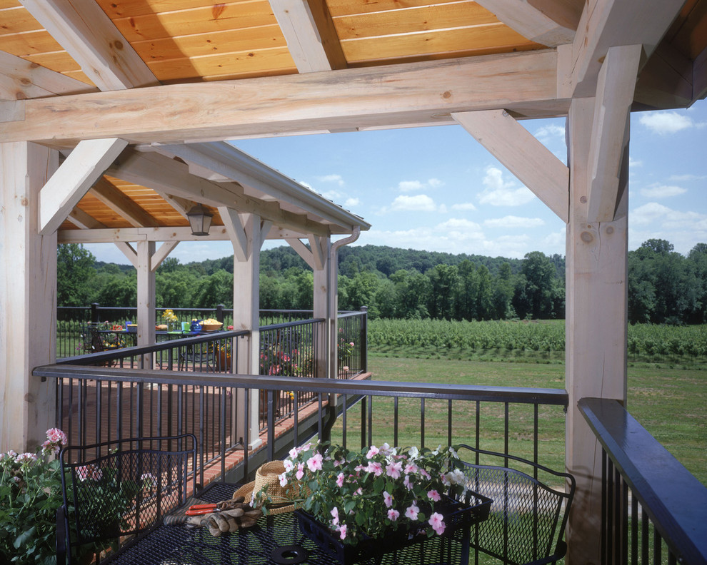 This is an example of a large country backyard patio in Charlotte with brick pavers and a pergola.