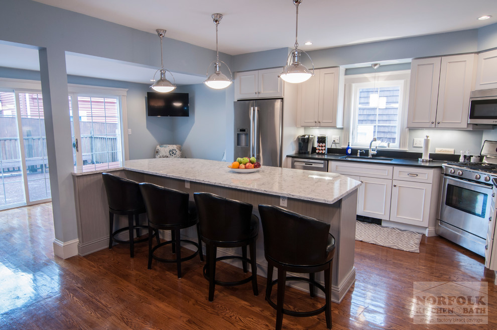 Example of a transitional l-shaped medium tone wood floor open concept kitchen design in Boston with a single-bowl sink, recessed-panel cabinets, white cabinets, granite countertops, stainless steel appliances and an island