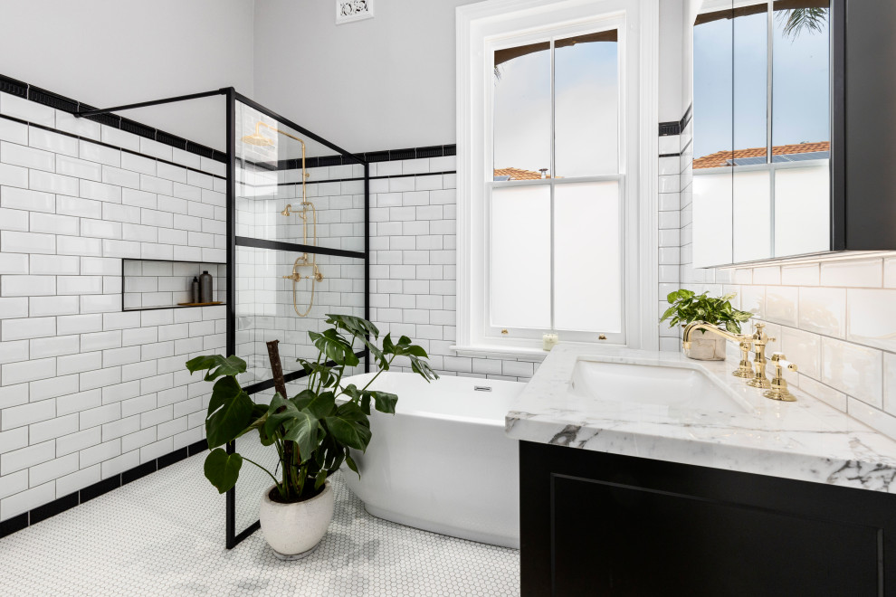 Photo of a large traditional ensuite bathroom in Melbourne with recessed-panel cabinets, black cabinets, a freestanding bath, a walk-in shower, white tiles, metro tiles, mosaic tile flooring, a submerged sink, marble worktops, an open shower, a single sink, a freestanding vanity unit, white floors and a wall niche.
