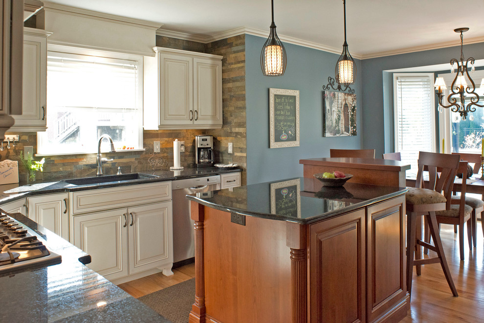 This is an example of a traditional eat-in kitchen in Detroit with a single-bowl sink, raised-panel cabinets, white cabinets, grey splashback, stainless steel appliances and slate splashback.