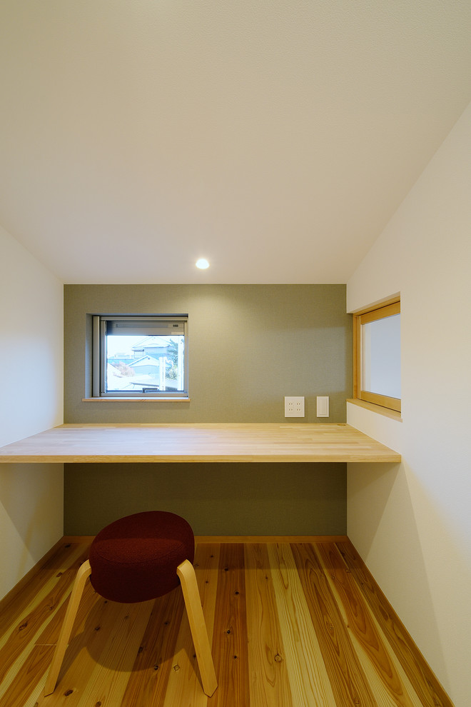 This is an example of a scandinavian home office in Other with white walls and medium hardwood floors.