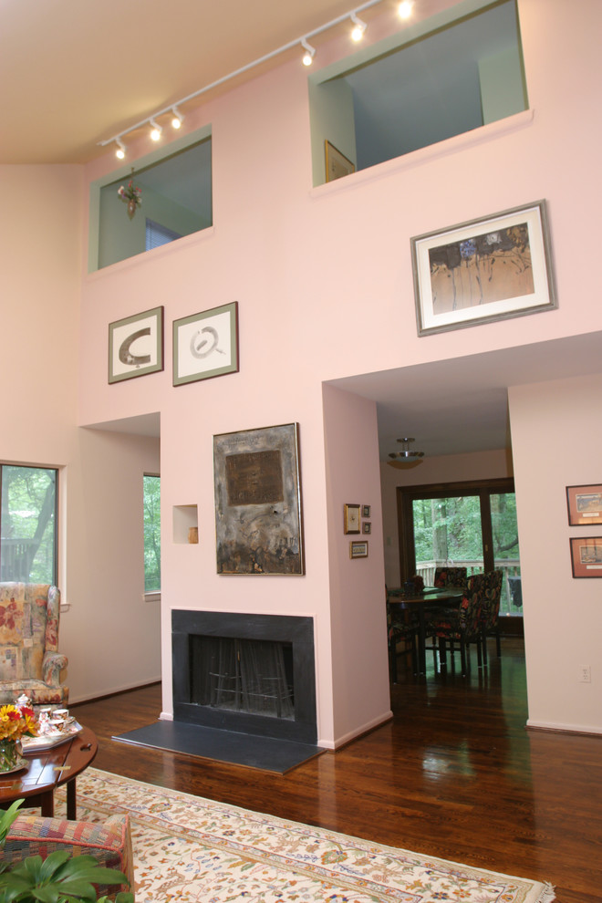 This is an example of a mid-sized eclectic open concept living room in Baltimore with pink walls, medium hardwood floors, a standard fireplace and a stone fireplace surround.