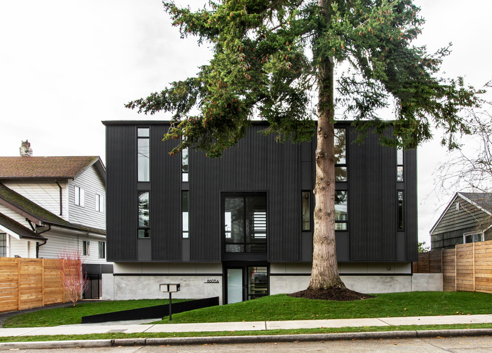 Inspiration for a large midcentury three-storey black house exterior in Seattle with metal siding, a gable roof, a shingle roof and a grey roof.