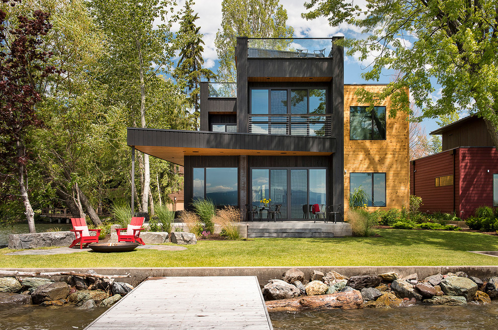 Inspiration for an expansive contemporary three-storey black exterior in Other with a flat roof and wood siding.