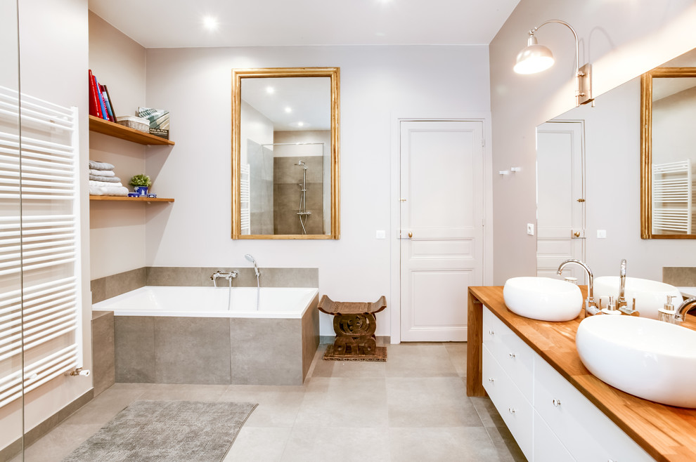 This is an example of a large modern master bathroom in Paris with an undermount tub, a curbless shower, a wall-mount toilet, gray tile, cement tile, grey walls, cement tiles, a drop-in sink, wood benchtops and grey floor.
