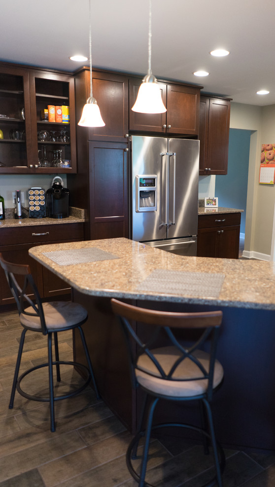 Example of a mid-sized u-shaped ceramic tile enclosed kitchen design with an undermount sink, shaker cabinets, dark wood cabinets, quartz countertops, brown backsplash, stainless steel appliances and a peninsula