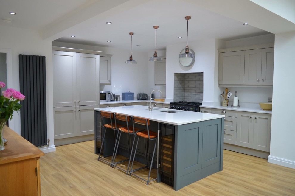 Large contemporary l-shaped open plan kitchen in Other with an undermount sink, shaker cabinets, grey cabinets, quartzite benchtops, white splashback, ceramic splashback, panelled appliances, medium hardwood floors, with island, brown floor and yellow benchtop.