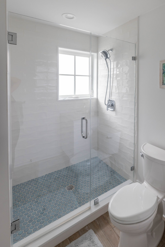 Пример оригинального дизайна: ванная комната среднего размера в морском стиле с душем в нише, унитазом-моноблоком, белой плиткой, плиткой кабанчик, белыми стенами, полом из плитки под дерево, душевой кабиной, коричневым полом и душем с распашными дверями