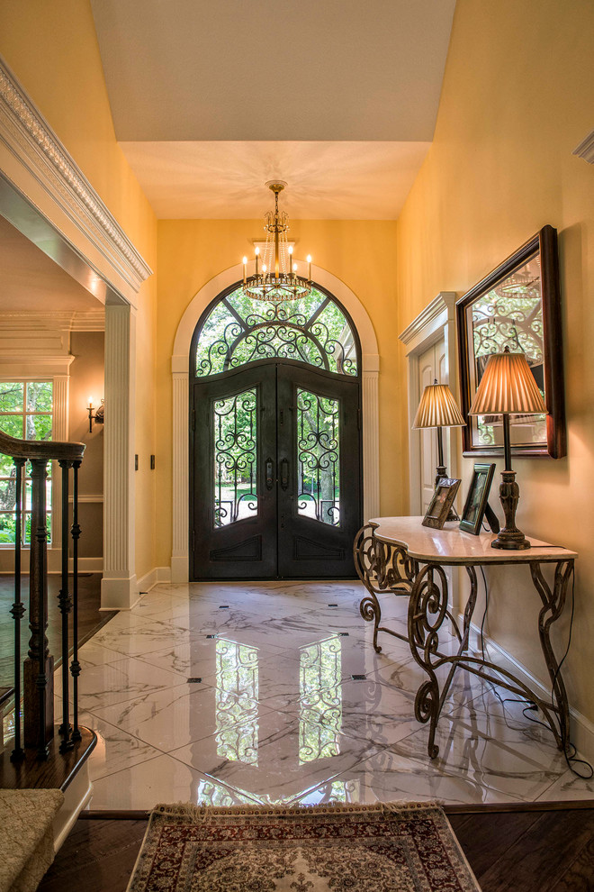 Inspiration for a large mediterranean foyer in Kansas City with yellow walls, porcelain floors, a double front door, white floor and a black front door.