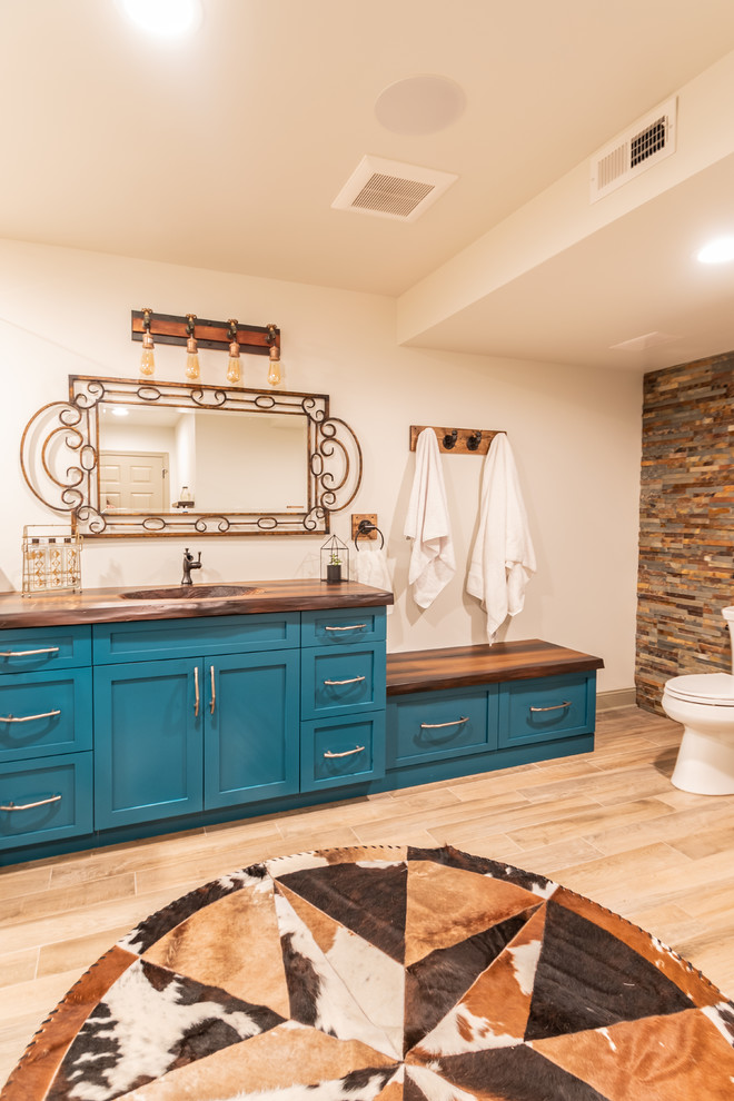 Design ideas for a mid-sized country 3/4 bathroom in Philadelphia with shaker cabinets, turquoise cabinets, an alcove shower, a one-piece toilet, beige tile, beige walls, porcelain floors, a console sink, concrete benchtops, brown floor, a hinged shower door and brown benchtops.