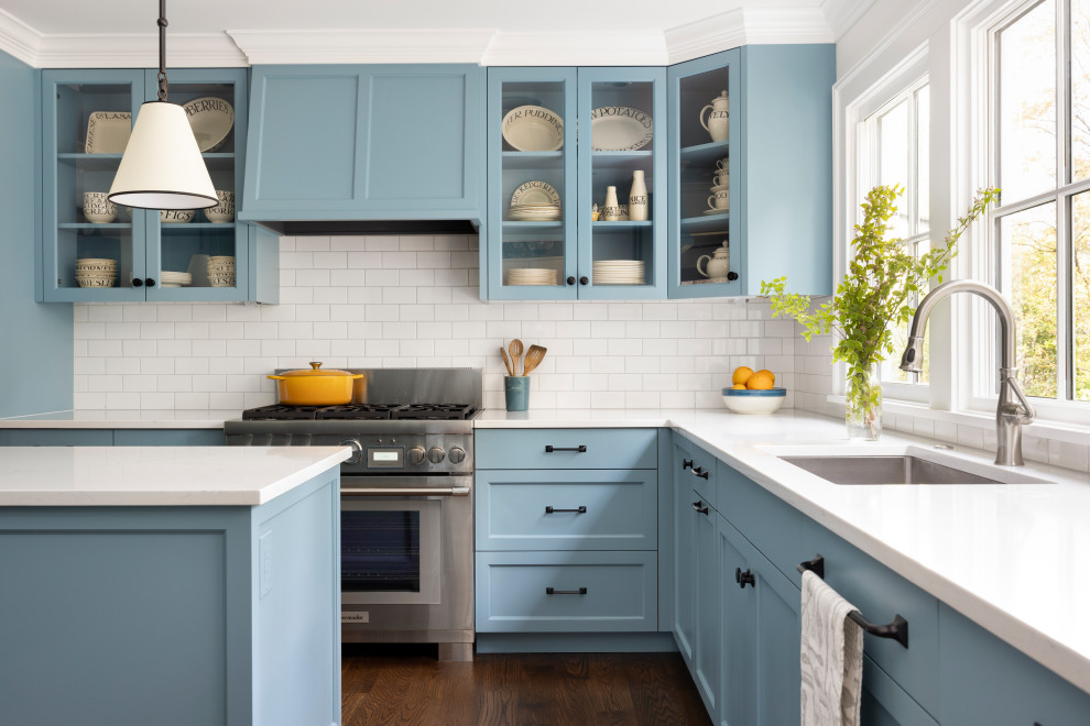 Exempel på ett mycket stort klassiskt vit vitt kök, med en undermonterad diskho, luckor med profilerade fronter, blå skåp, bänkskiva i kvarts, vitt stänkskydd, stänkskydd i keramik, rostfria vitvaror, mellanmörkt trägolv och en köksö