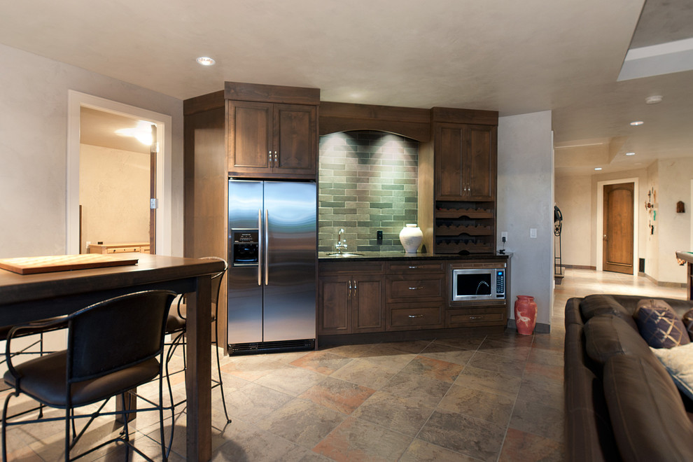 Photo of a mid-sized contemporary single-wall wet bar in Vancouver with an undermount sink, recessed-panel cabinets, dark wood cabinets, grey splashback, stone tile splashback, slate floors and beige floor.