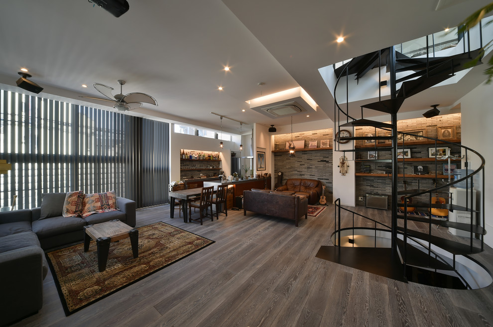This is an example of a large industrial open concept living room in Tokyo with a home bar, white walls and grey floor.