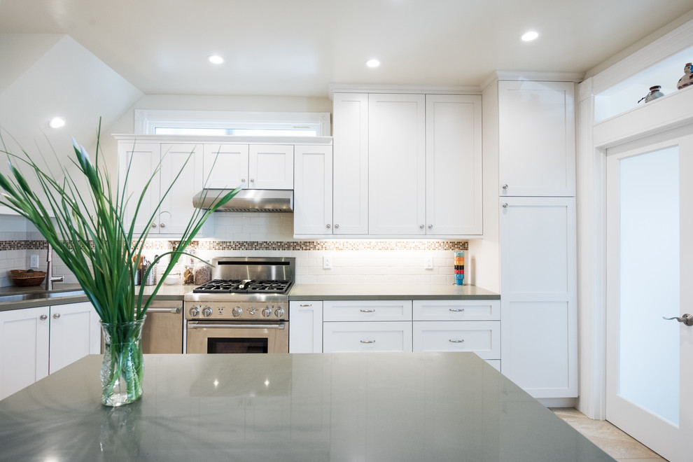 Enclosed kitchen - large traditional u-shaped marble floor and beige floor enclosed kitchen idea in San Francisco with shaker cabinets, white cabinets, solid surface countertops, white backsplash, subway tile backsplash, stainless steel appliances and an island