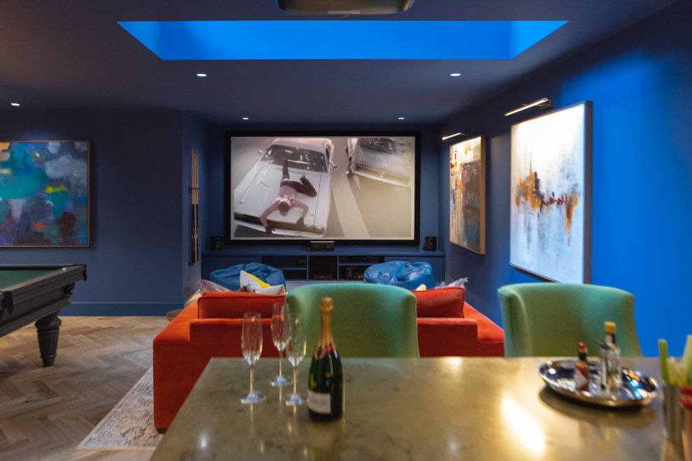 Large trendy underground medium tone wood floor and brown floor basement photo in London with a home theater, blue walls and no fireplace