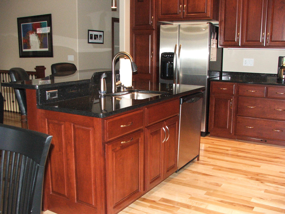 Mid-sized elegant l-shaped eat-in kitchen photo with an undermount sink, raised-panel cabinets, medium tone wood cabinets, stainless steel appliances and an island
