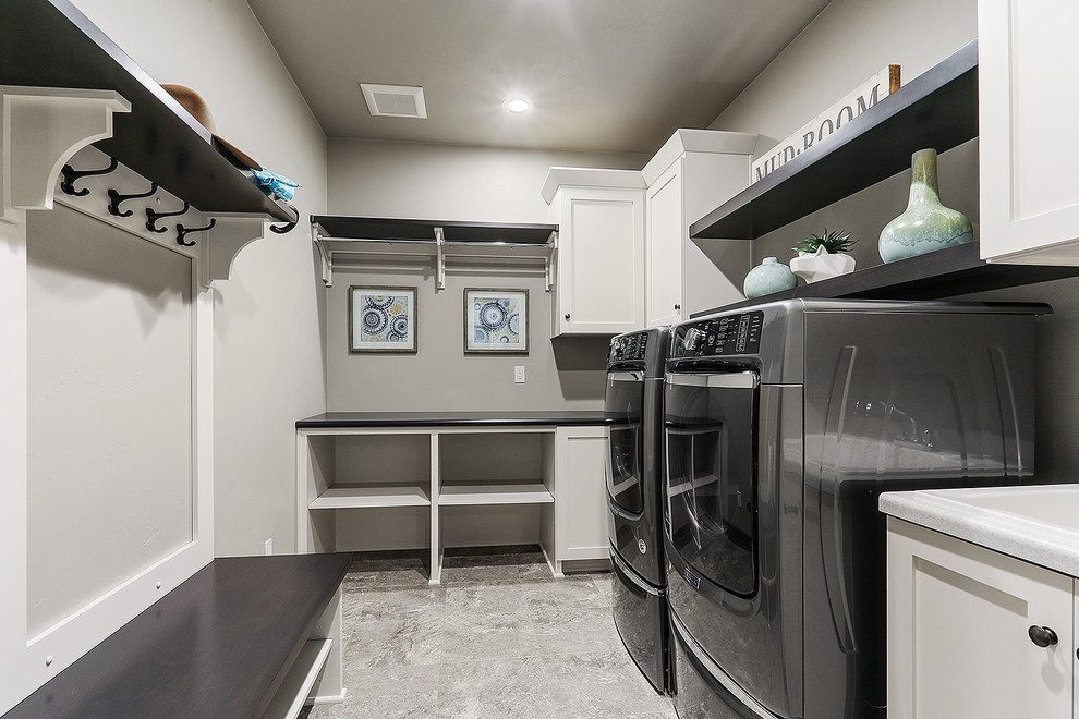 This is an example of a large transitional l-shaped utility room in Other with white cabinets, grey walls, vinyl floors, a side-by-side washer and dryer, grey floor and shaker cabinets.