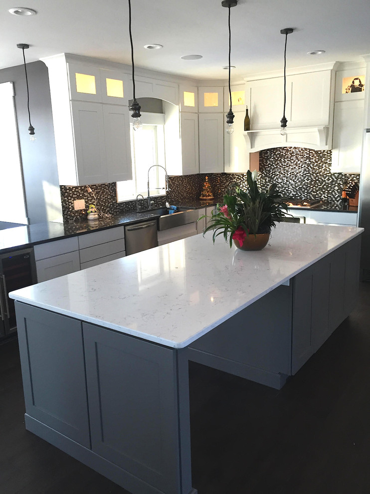 Example of a mid-sized transitional l-shaped dark wood floor and black floor kitchen design in Minneapolis with a farmhouse sink, shaker cabinets, white cabinets, quartzite countertops, multicolored backsplash, mosaic tile backsplash, stainless steel appliances and an island