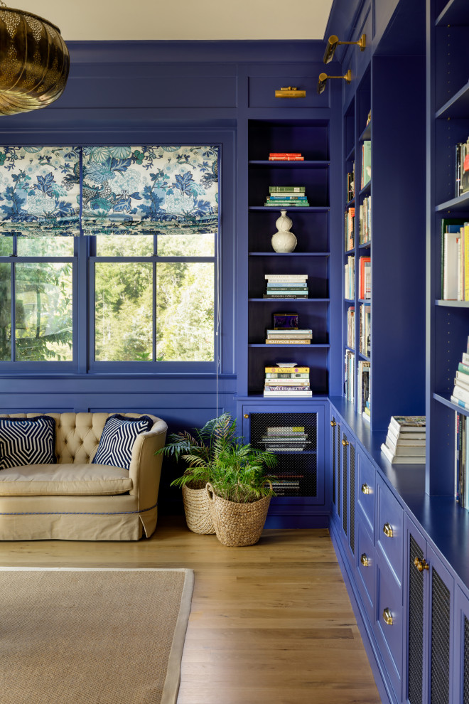 Réalisation d'un bureau champêtre avec une bibliothèque ou un coin lecture et un mur bleu.