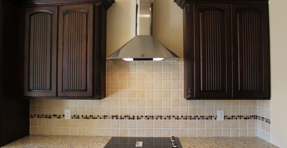 Kitchen - kitchen idea in Austin with dark wood cabinets, beige backsplash, stainless steel appliances and an island