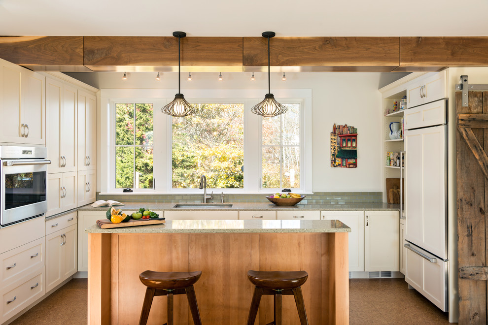 Design ideas for a mid-sized country kitchen in Boston with an undermount sink, shaker cabinets, white cabinets, recycled glass benchtops, panelled appliances, cork floors and with island.