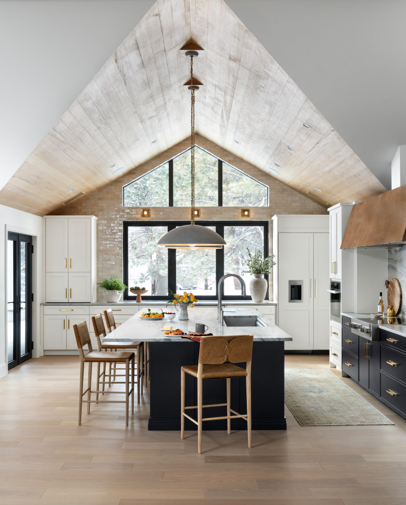 Transitional l-shaped open plan kitchen in Denver with panelled appliances, light hardwood floors, with island and timber.