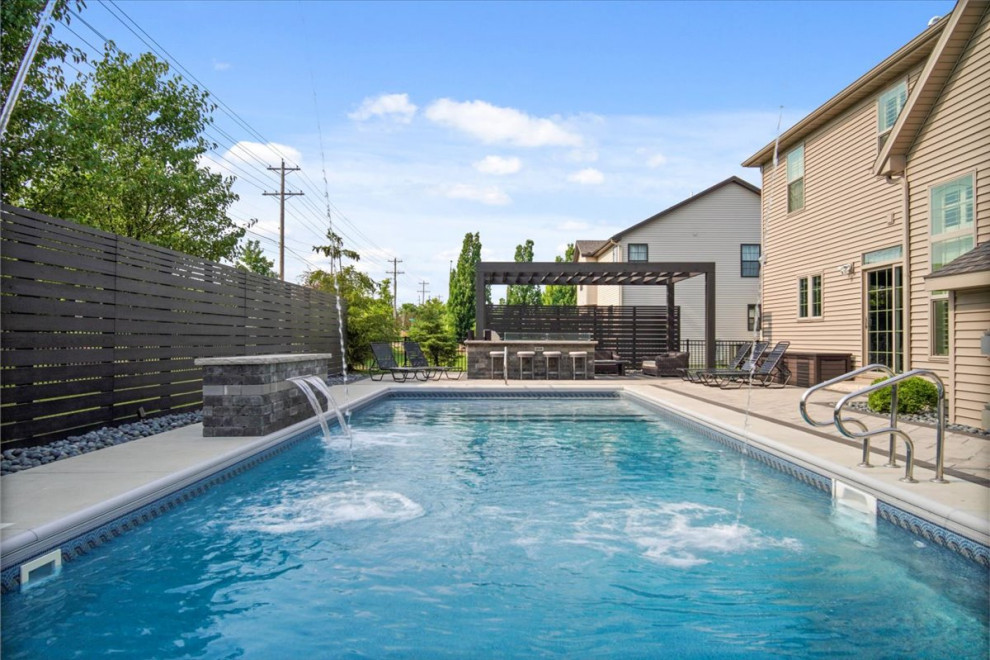 Ejemplo de piscina con fuente alargada moderna de tamaño medio rectangular en patio trasero con adoquines de hormigón