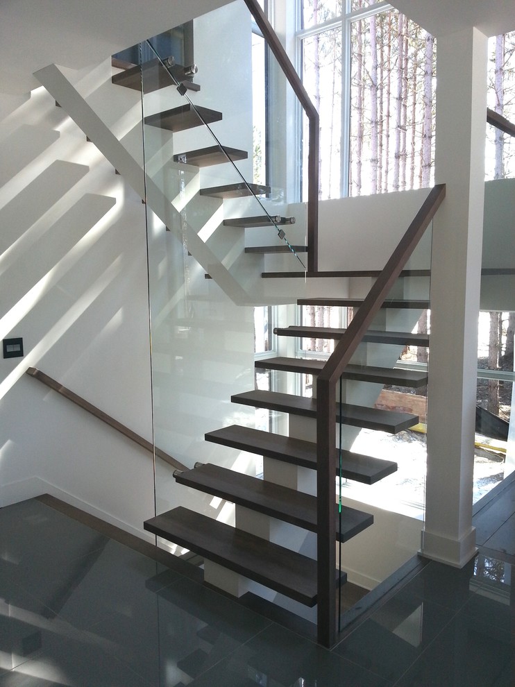 Design ideas for a mid-sized contemporary wood u-shaped staircase in Montreal with open risers and glass railing.
