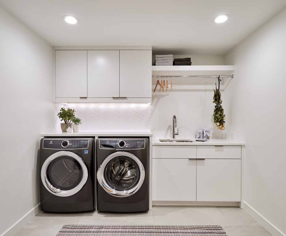 Idéer för små funkis parallella vitt tvättstugor enbart för tvätt, med en undermonterad diskho, släta luckor, vita skåp, bänkskiva i kvarts, vitt stänkskydd, klinkergolv i porslin och grått golv